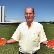 Enildo Gomes, fundador da Pizzaria Dom Bosco, com duas pizzas na mão em frente ao Congresso Nacional